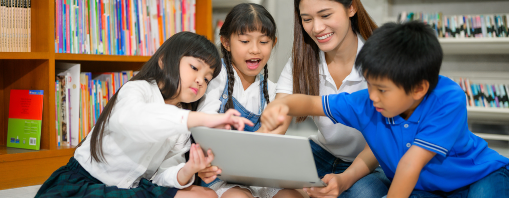Image of school children looking at a computer with a teacher in a library